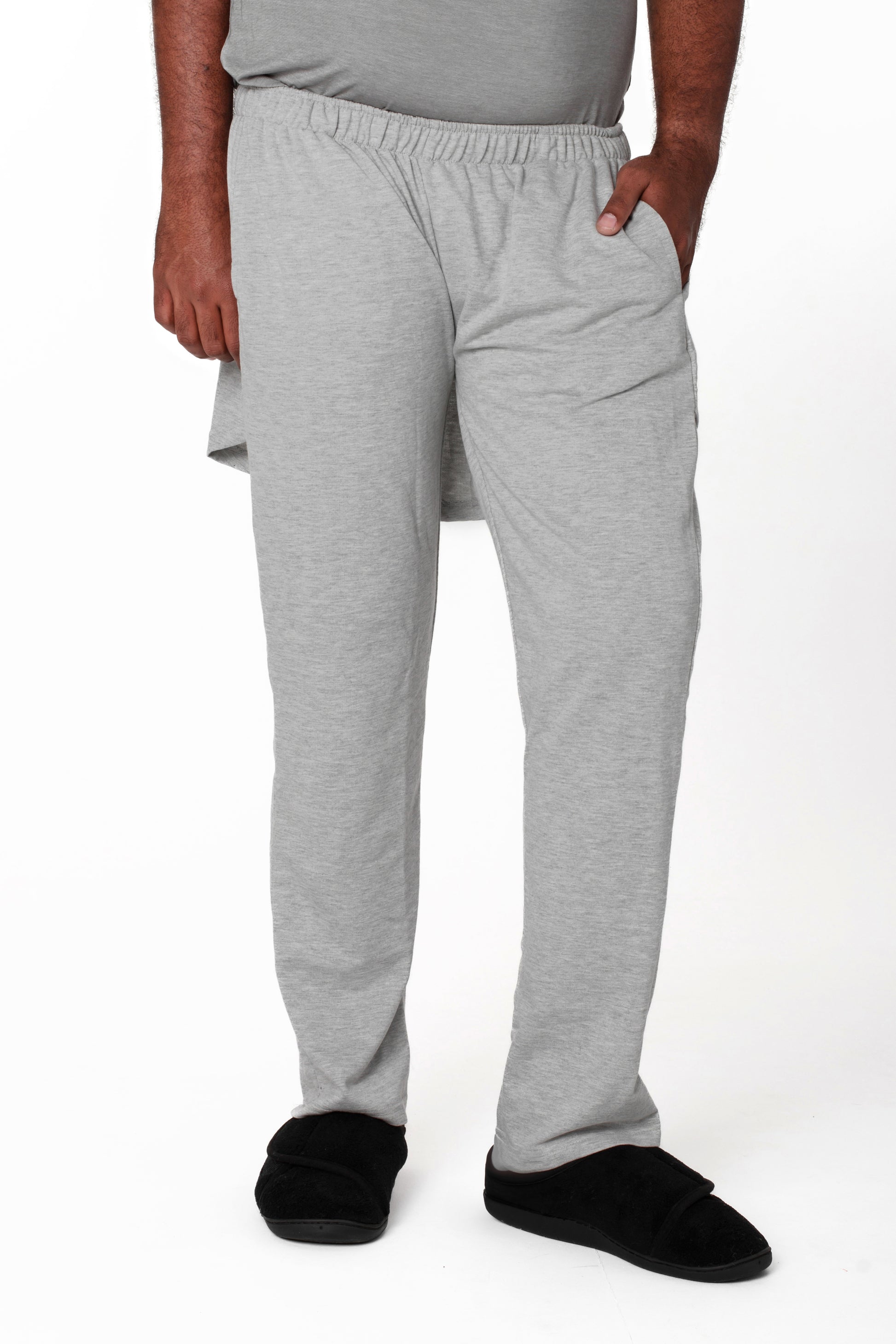 A model wearing unisex gray fleece adaptive pants with an open back design.