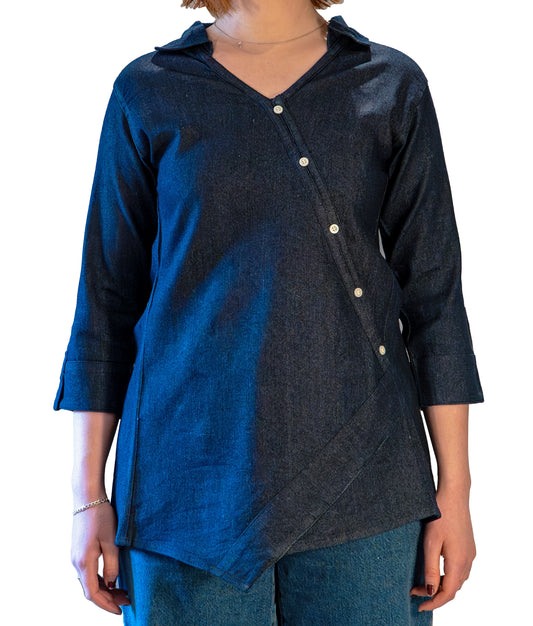 A woman wearing a navy blue denim top with a round neckline and three-quarter sleeves, featuring an open back with two snap closures at the shoulders.